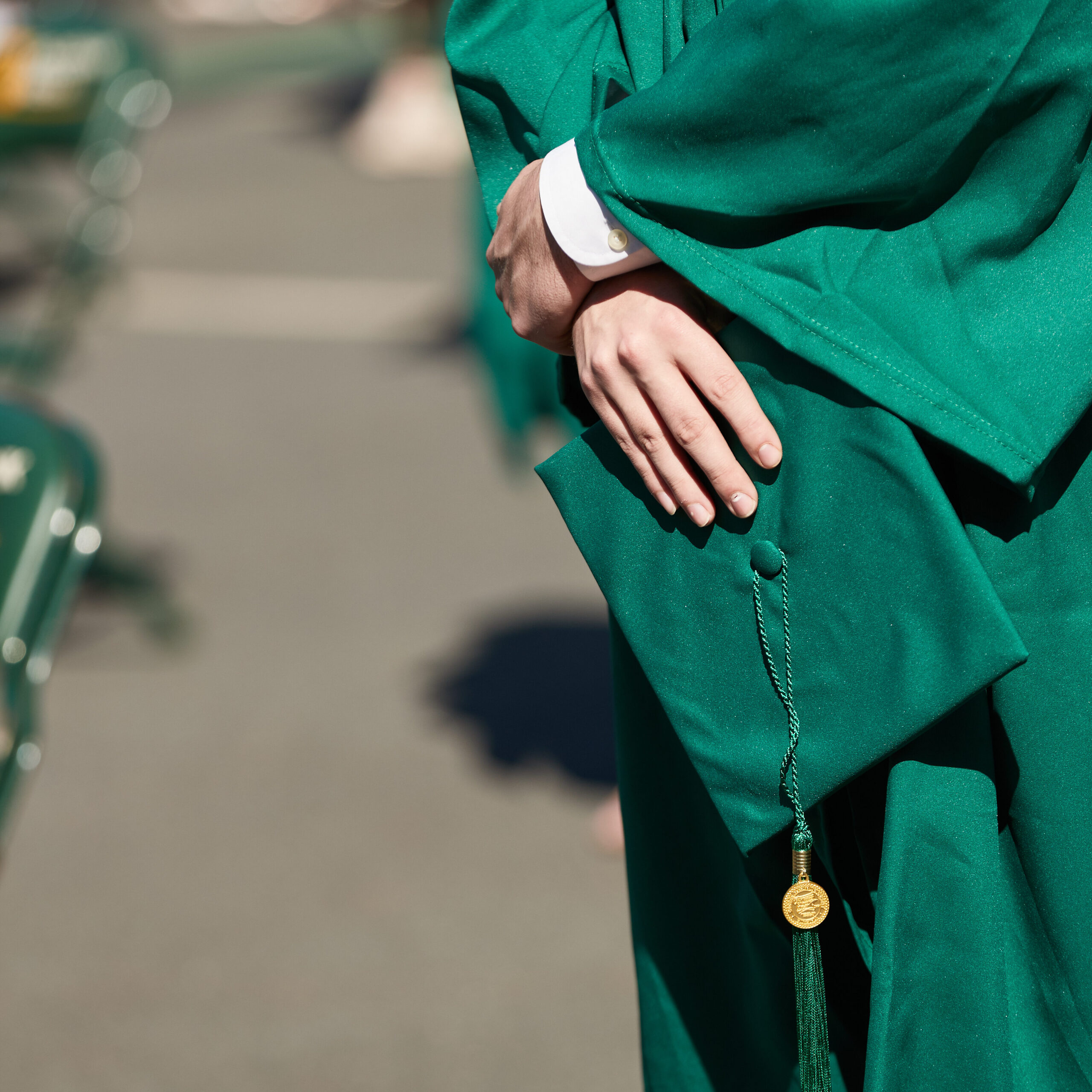 student in full regalia holding grad cap