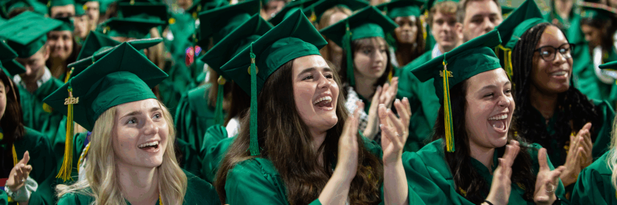 George Mason graduating students cheering and clapping at the CEHD Degree Celebration in EagleBank Arena